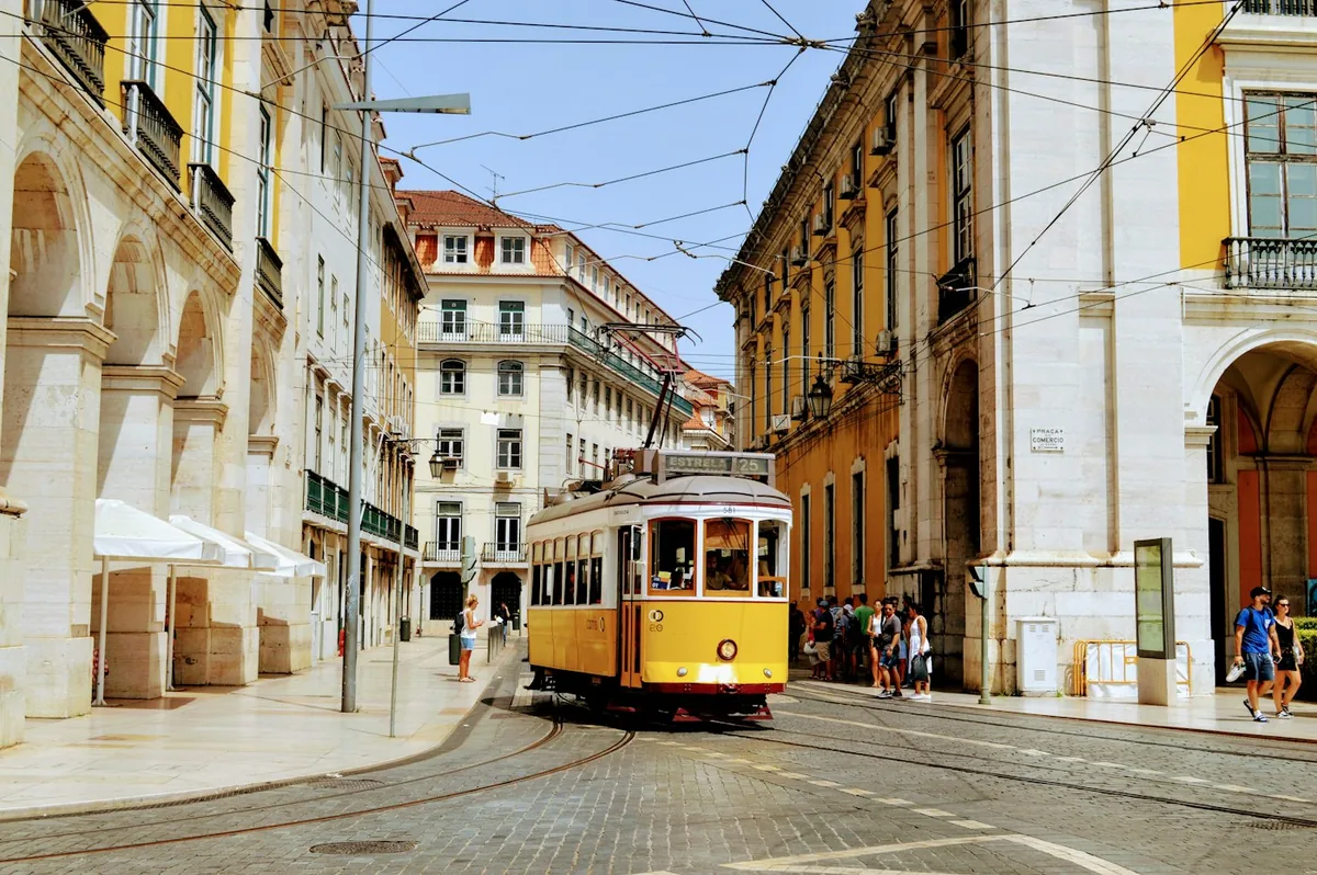 A yellow tram beside the historic buildings around Praça do Comércio, Lisbon